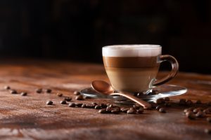 Cup of coffe with milk on a dark background. Hot latte or Cappuccino prepared with milk on a wooden table with copy space